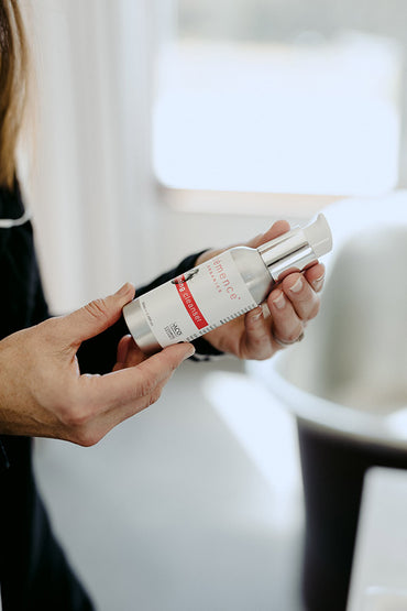 A woman holding a skin care product.