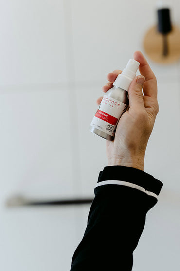 A woman holding a spritz skin care product.