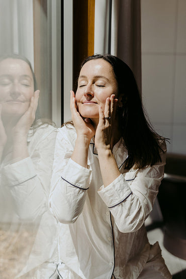 A woman applying a sunscreen skin care product to her face.