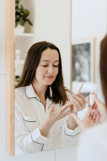 A woman dispensing a skin care product onto her finger.