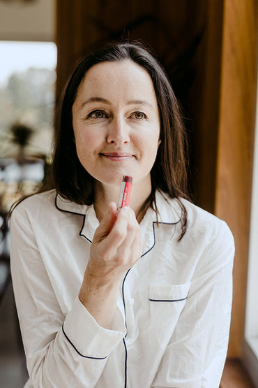 A woman applying a lip balm to her lips.