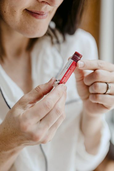 A woman applying a lip balm to her lips.