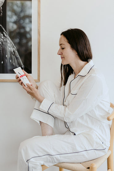 A woman sitting in a chair holding a skin care product.