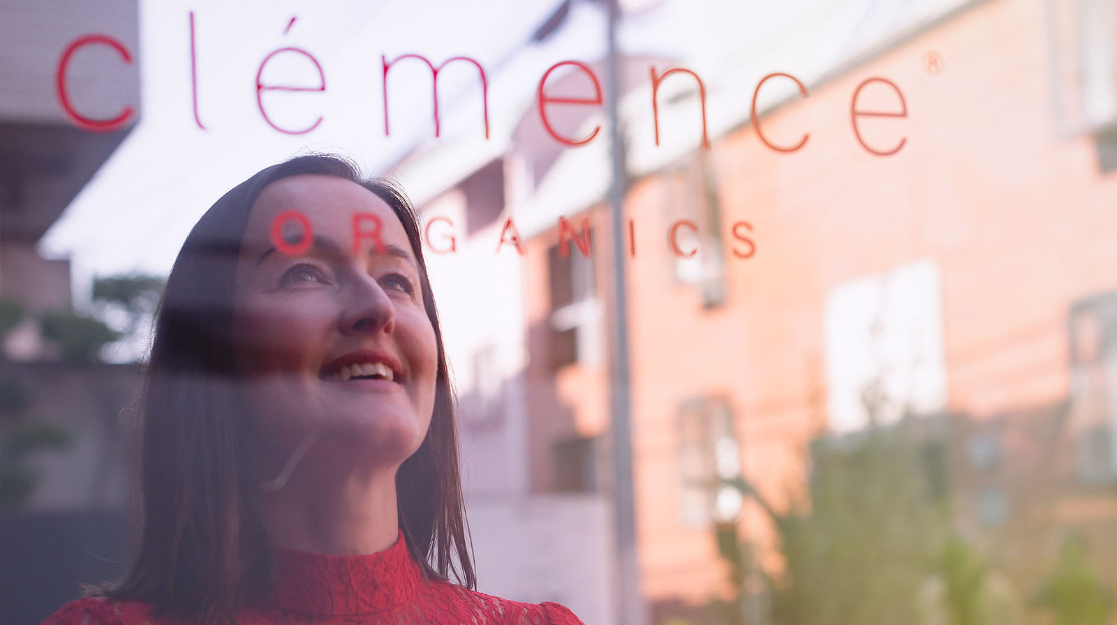 The reflection of a woman looking into a mirror. Written on the mirror are the words Clémence Organics.