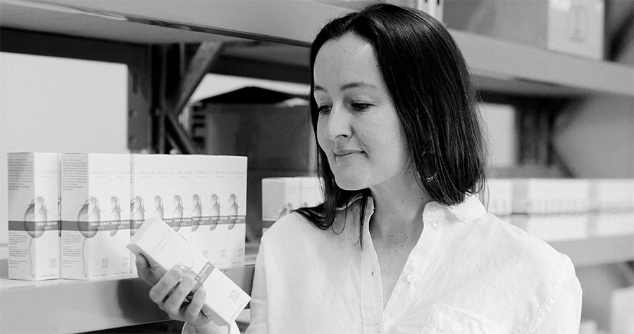 A black and white image of a woman holding a Clémence Organics product.