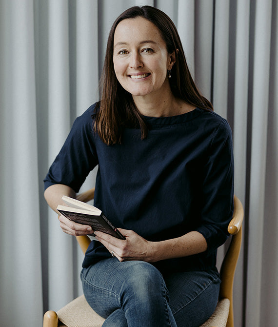 Bridget Carmady sitting on a seat holding a book and smiling.