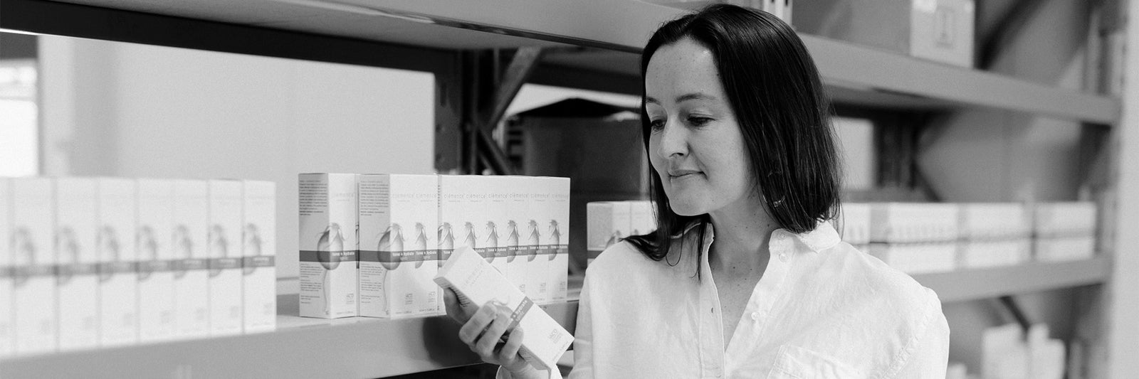 A woman holding an organic Australian skin care product in a warehouse.