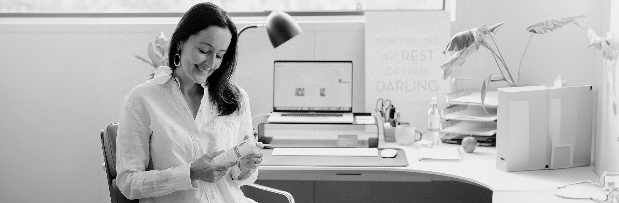 A woman sitting at an office table holding a Clémence Organics product.