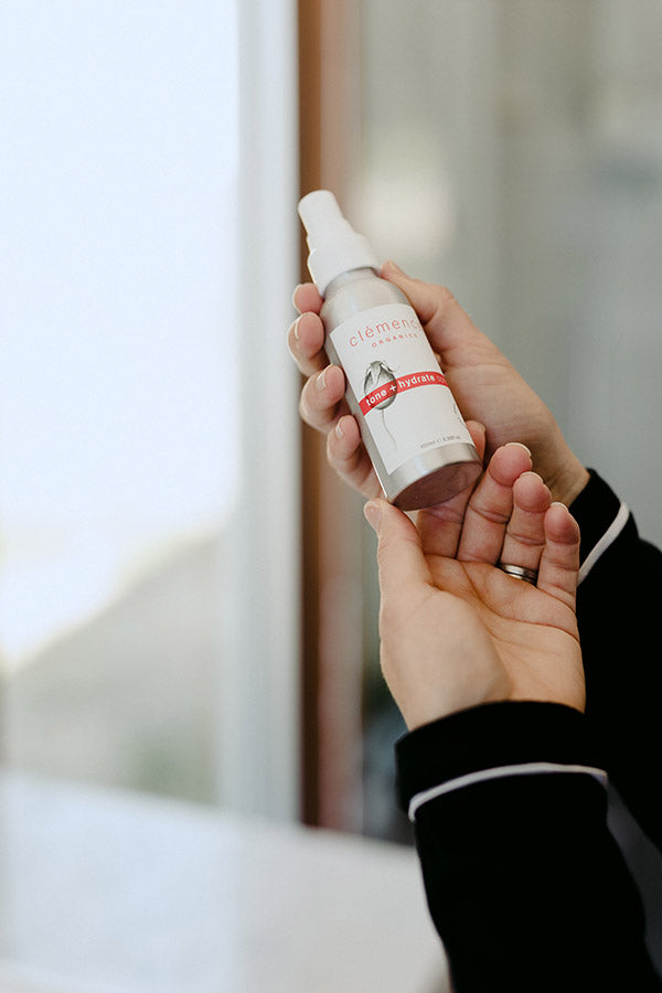 A woman's hands holding a spritz skin care product.