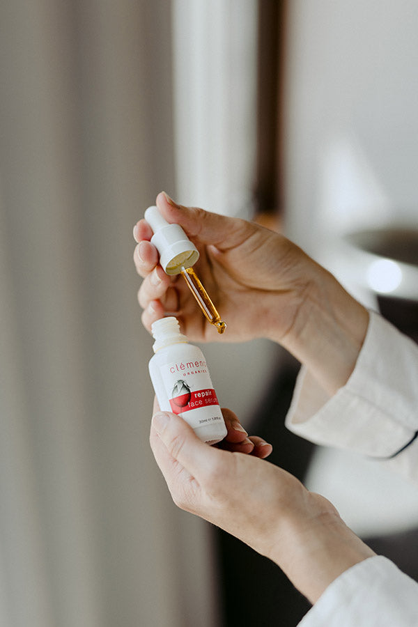 A woman's hands holding a serum skin care product.