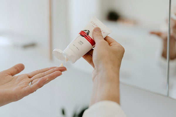 A woman's hands dispensing a skin care product onto her finger.