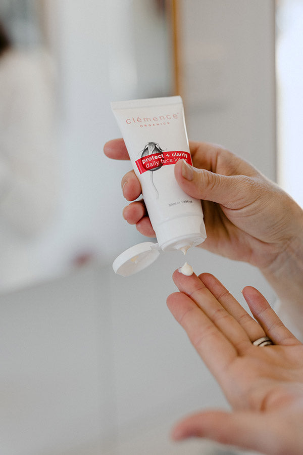 A woman dispensing a sunscreen skin care product onto her finger.