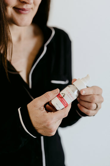A woman holding a skin care product in her hands.
