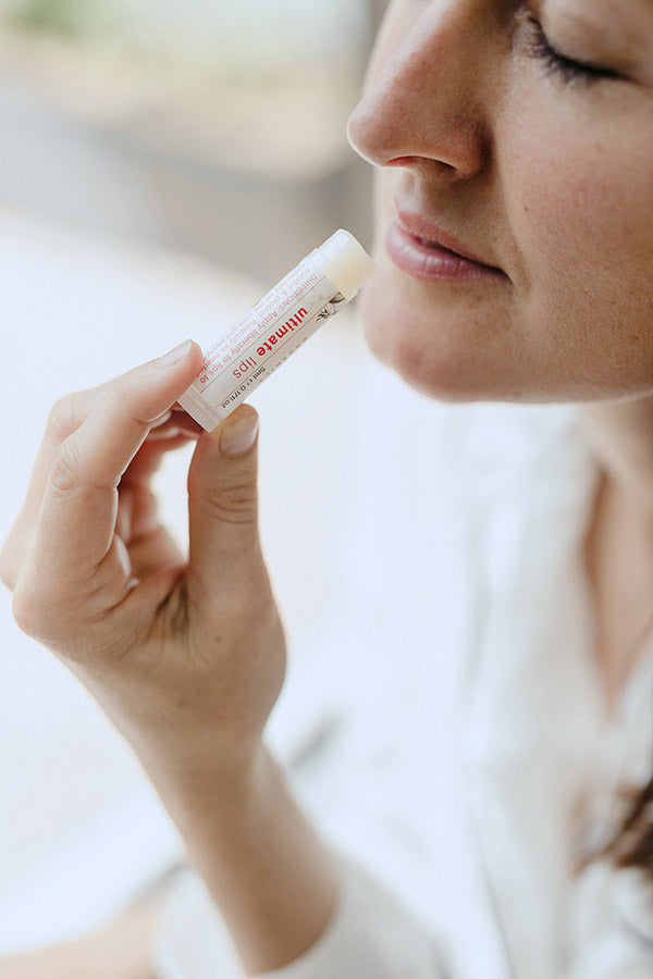 A woman applying a lip balm to her lips.