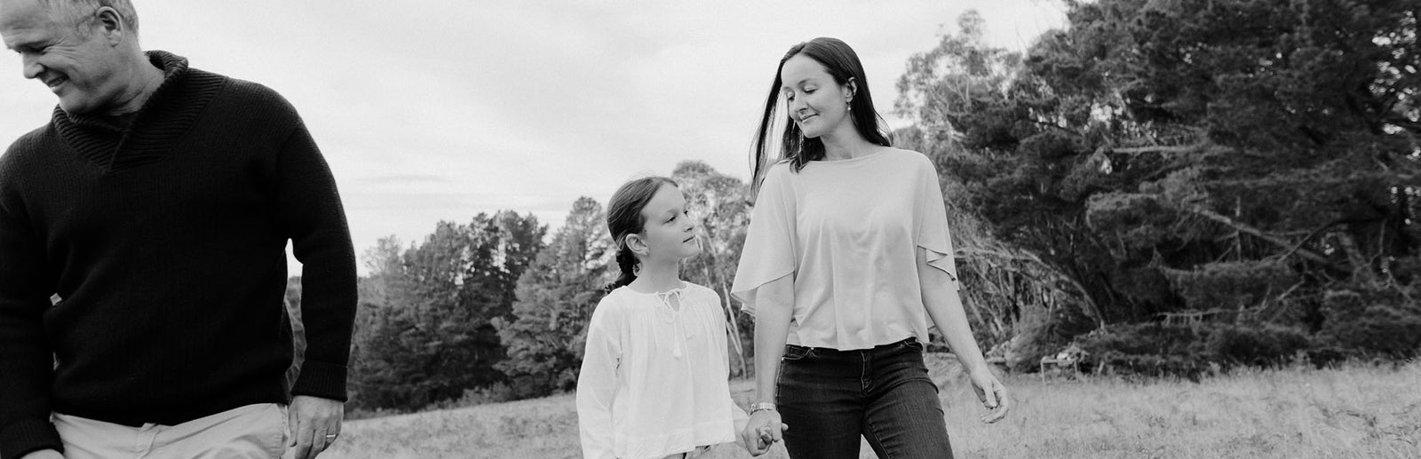 A woman, man and child walking through a field.