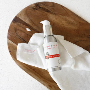 The Clémence Organics Refining Cleanser 100ml pump bottle and Face Cloth laying on a wooden board.